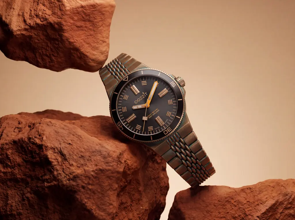 Concept product shot: a bronze diver’s watch wedged between red rocks.