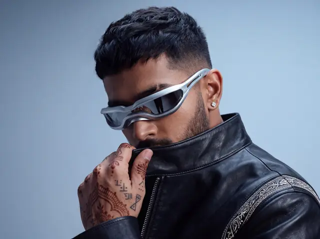 Concept campaign for eyewear: a man in wraparound chrome sunglasses and a leather jacket, hand at his collar.
